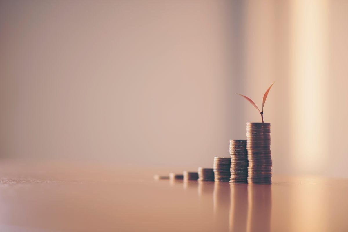 A piggy bank put on the stacking gold coins and blackboard house and clock on the vintage blue background, saving money for buy a new real estate or loan for planned investment in the future concept.